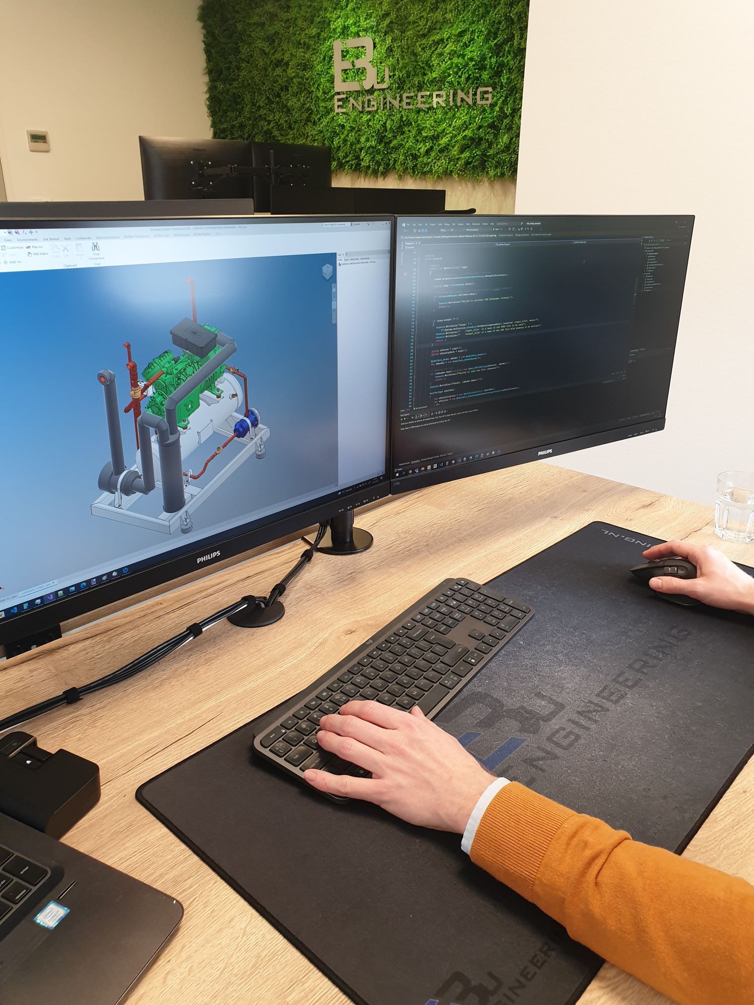 CAD-model en softwarecode naast elkaar op engineeringmonitoren.